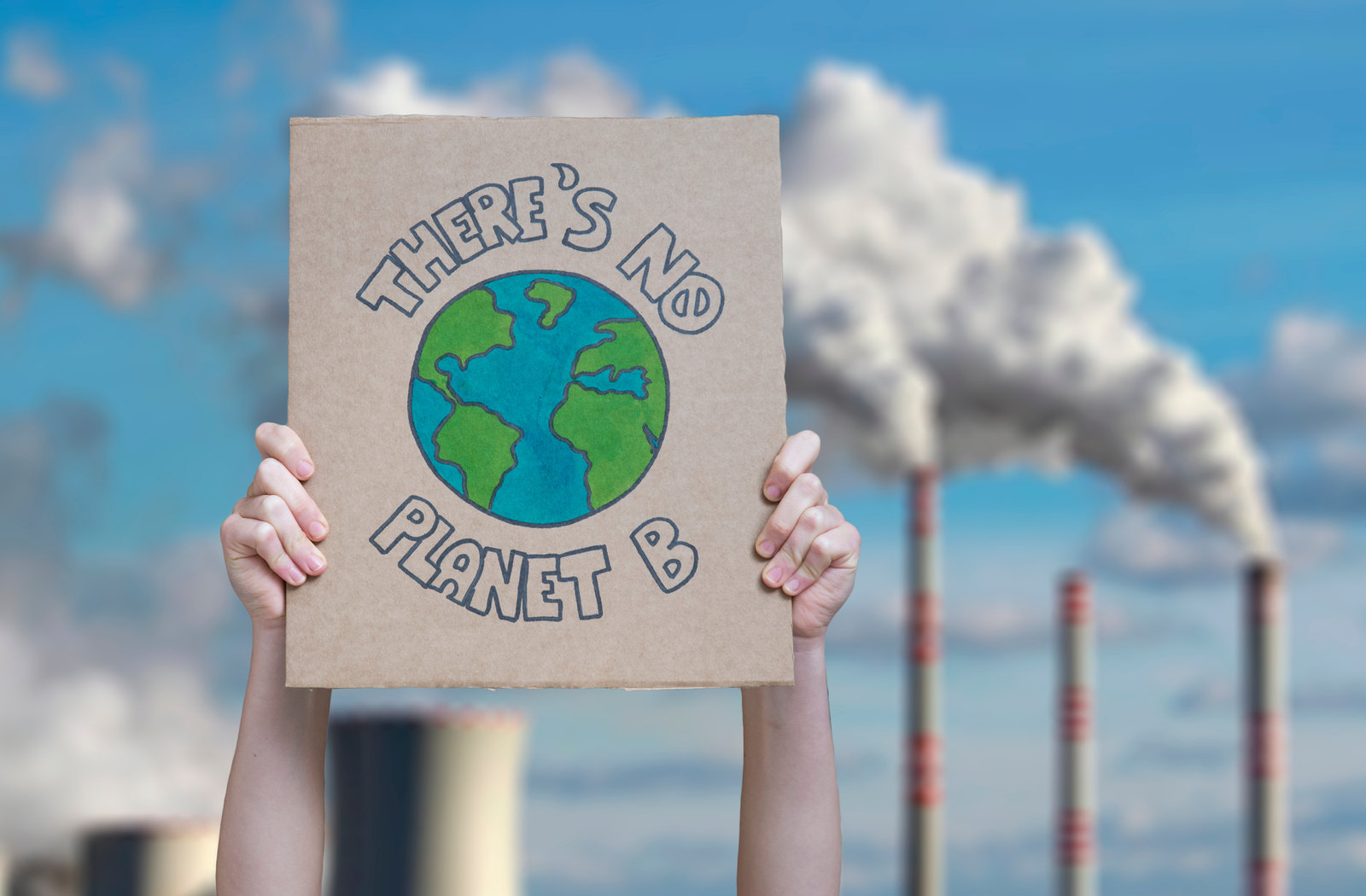 Climate action sign in front of industrial infrastructure